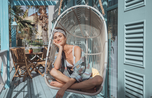 Girl in rotan swinging chair on patio