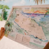 Hands holding a colorful illustrated map of Aruba titled 'Aruba Romance Treasure Map' at Boardwalk Boutique Hotel